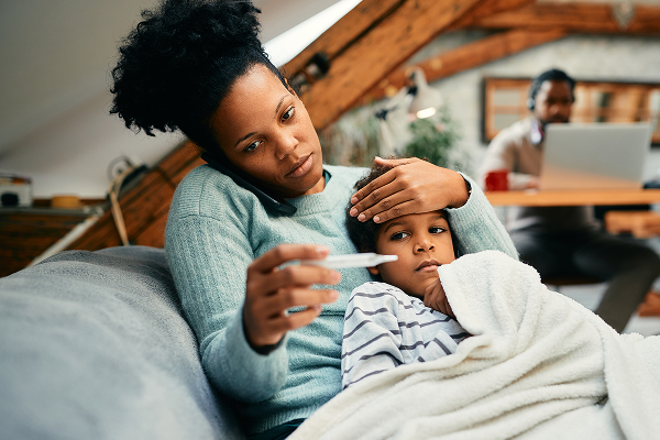 woman holding sick child taking its temperature